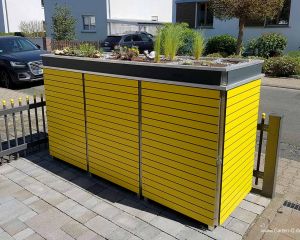 Die gelbe HPL Mülltonnenbox mit Dachbegrünung