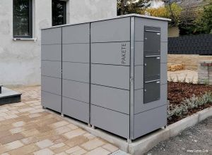 Der graue Paketkasten mit integrierter Paketbox im Vorgarten